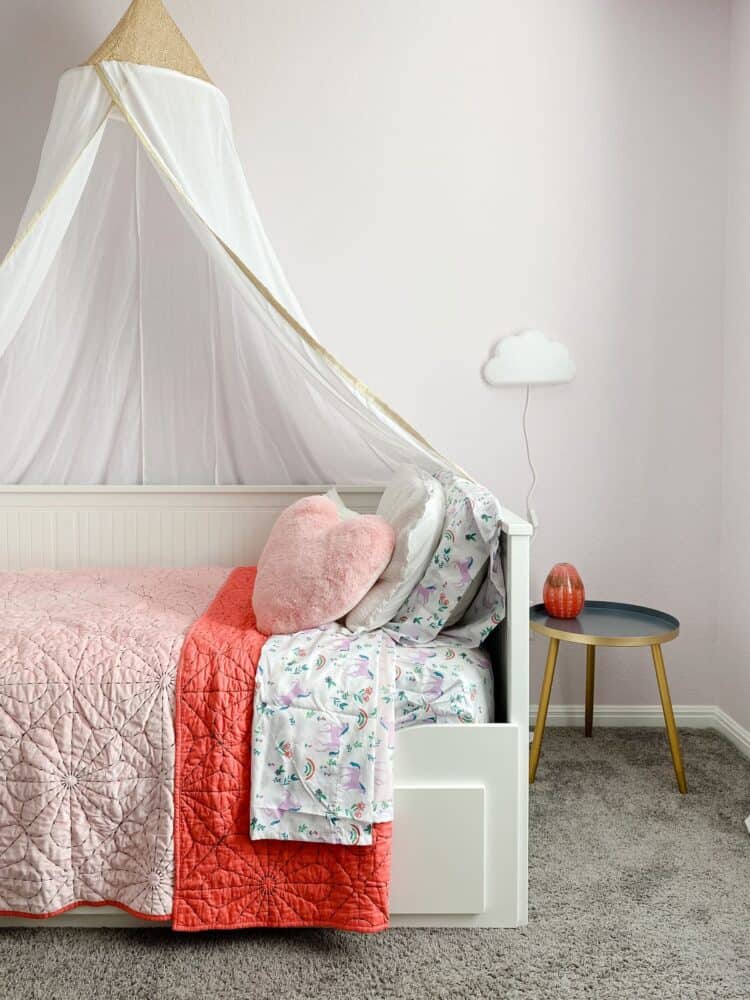 corner of girl's bedroom with pink bedding and princess canopy