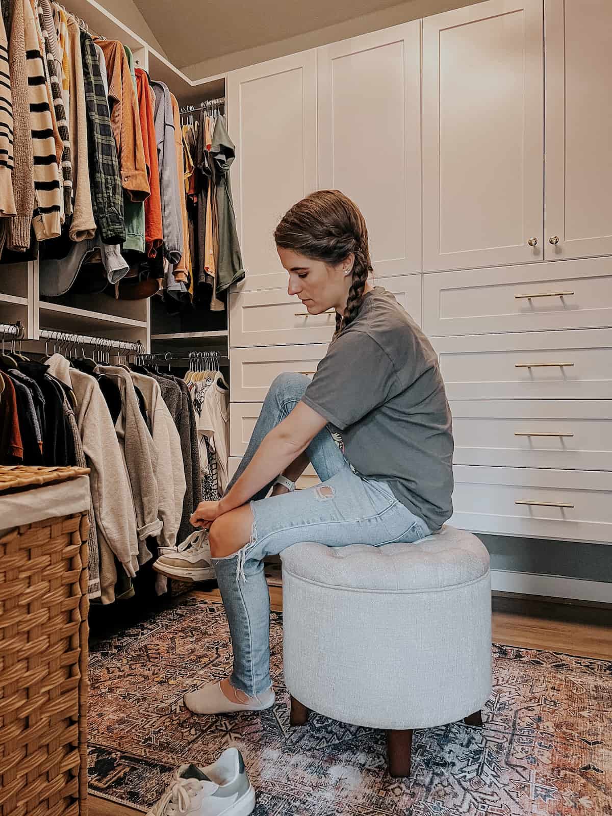 woman sitting on an ottoman to put on a pair of shoes 