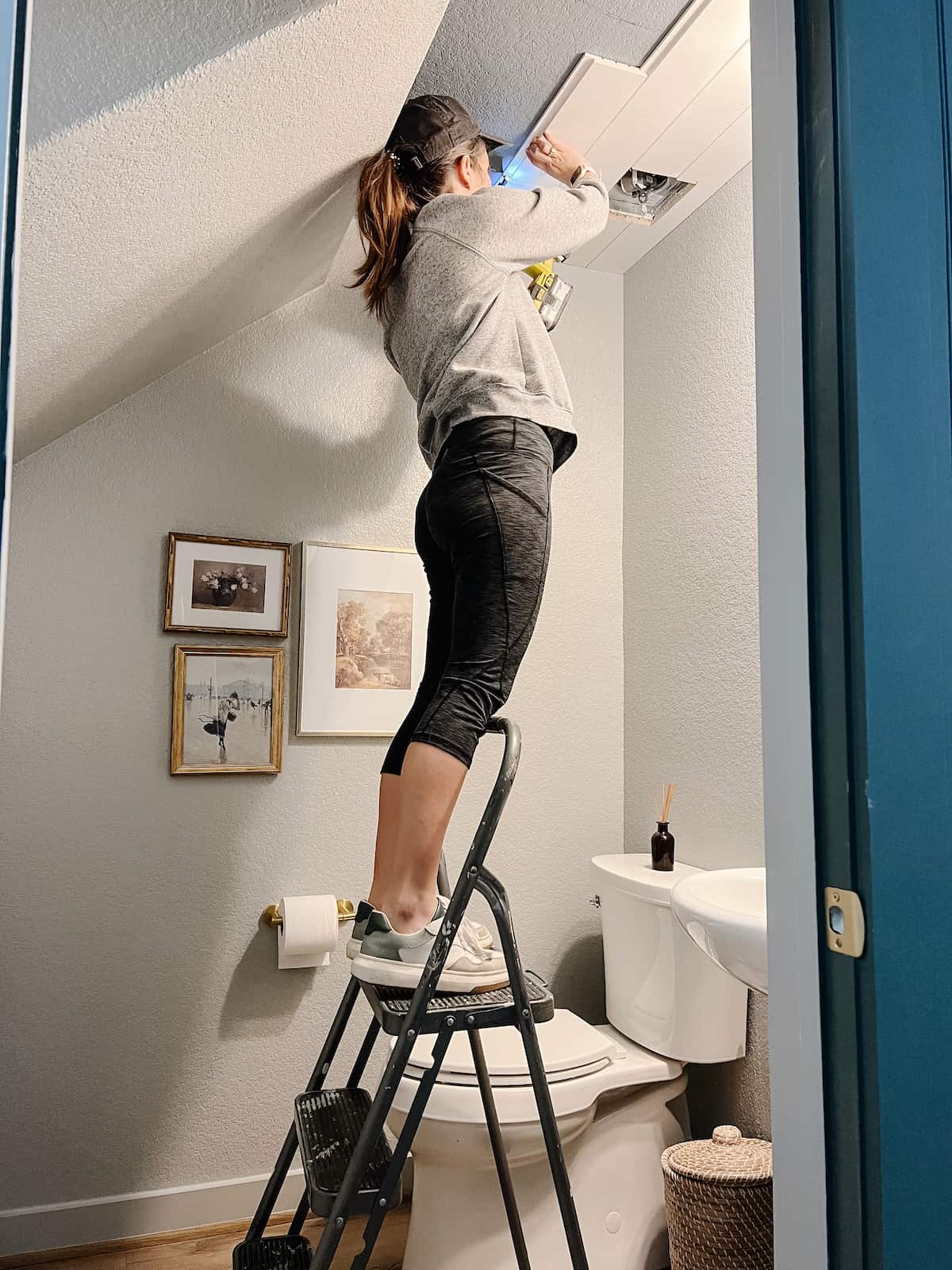 woman installing a shiplap plank on a powder room ceiling 