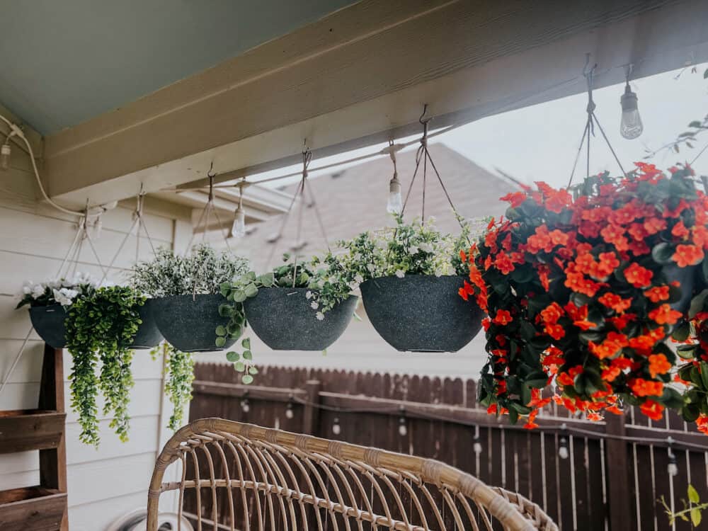 Close up of faux plants in hanging planters on a back patio