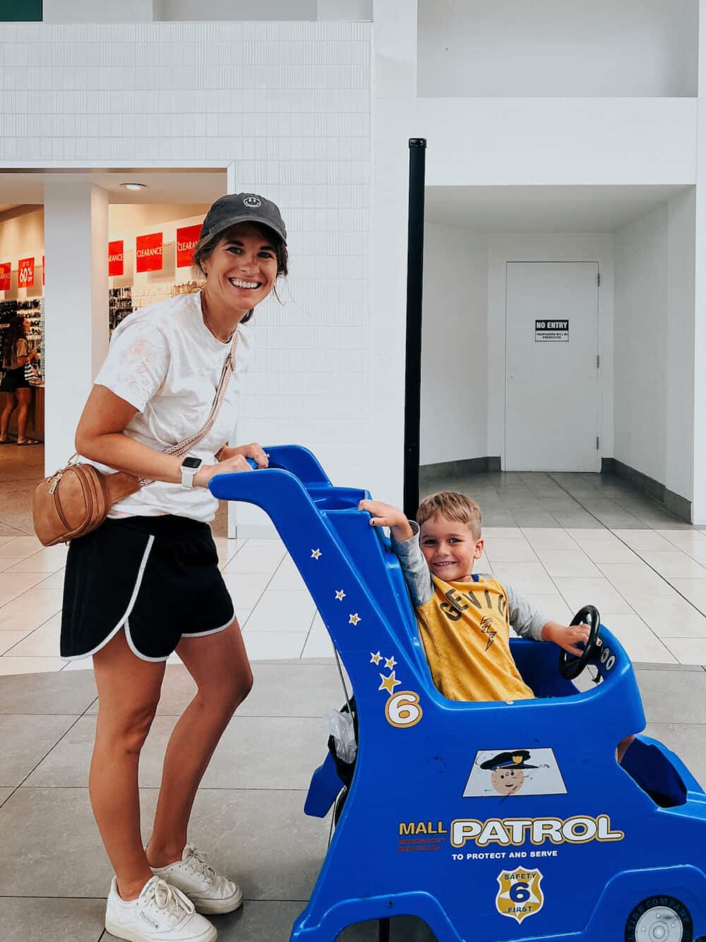 young boy in a mall stroller posing with his mom