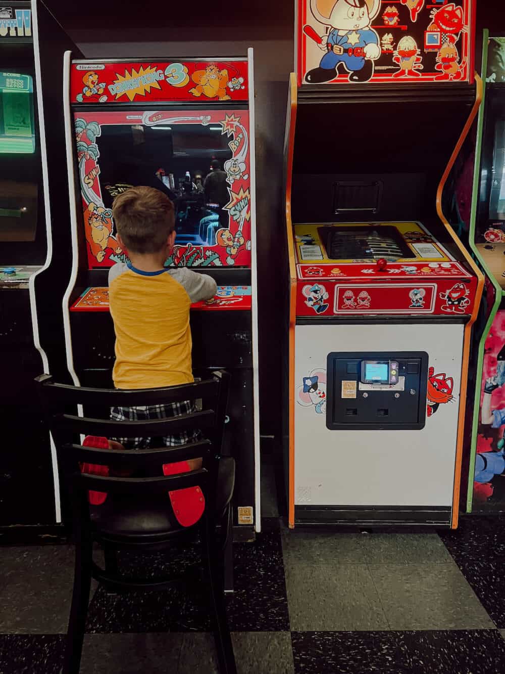 young boy playing a pinball machine at an arcade