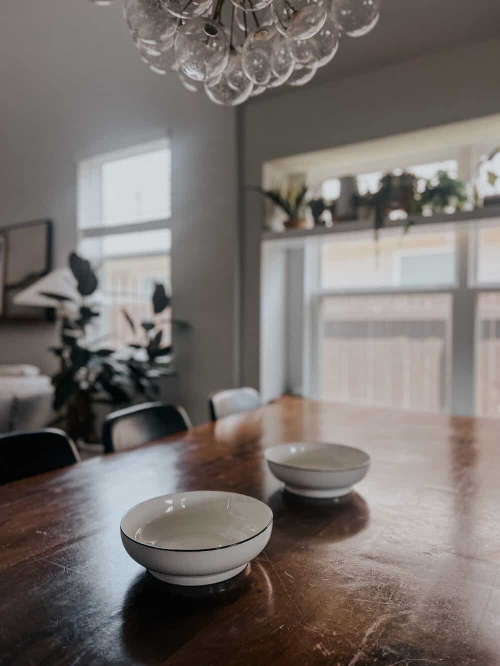 dining room table with two bowls being used as a centerpiece 