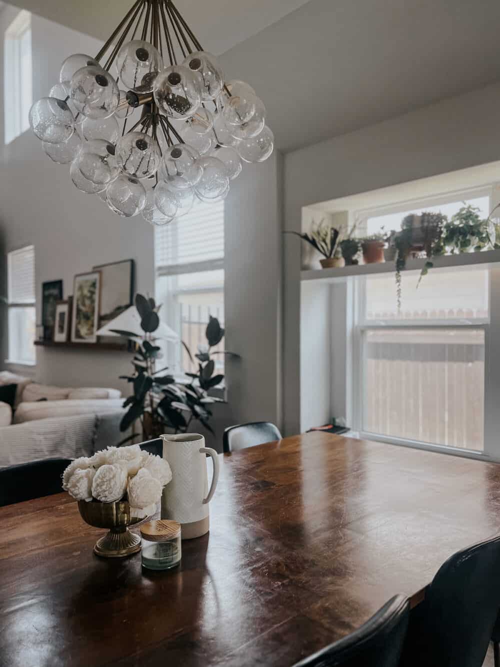 dining room table with flowers, a pitcher, and a candle as a centerpiece