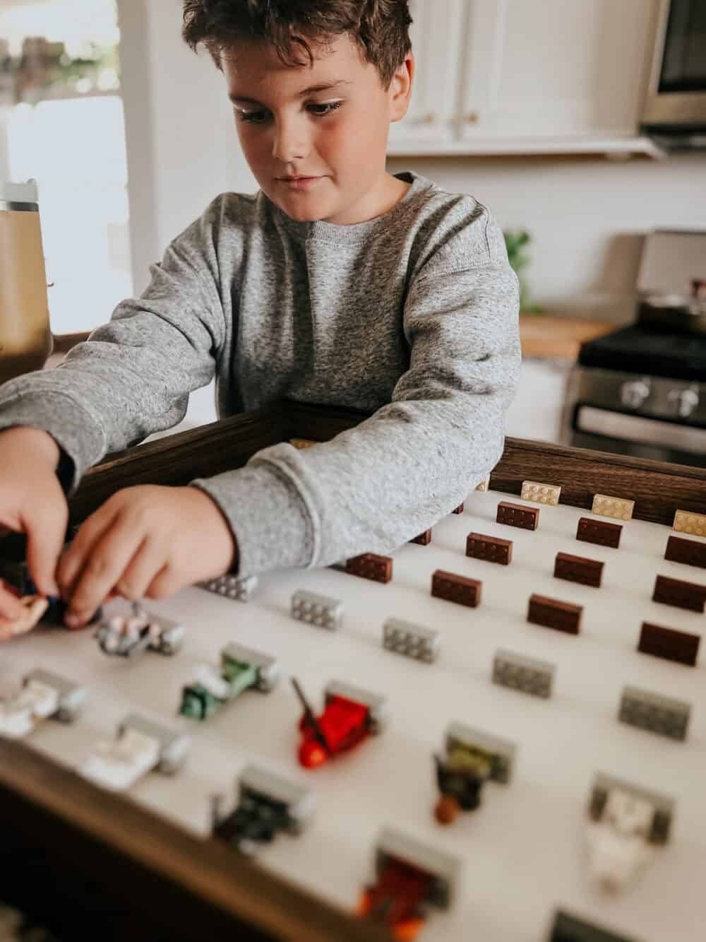 boy adding lego minifigures to a lego minifig display