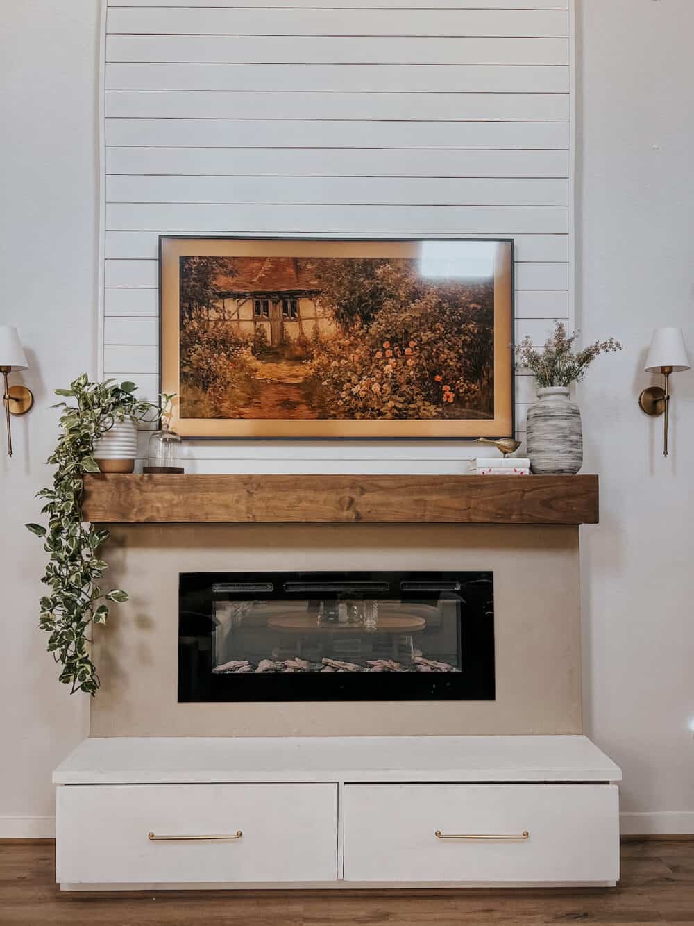 Electric fireplace with a wood mantel and a frame tv hanging above it