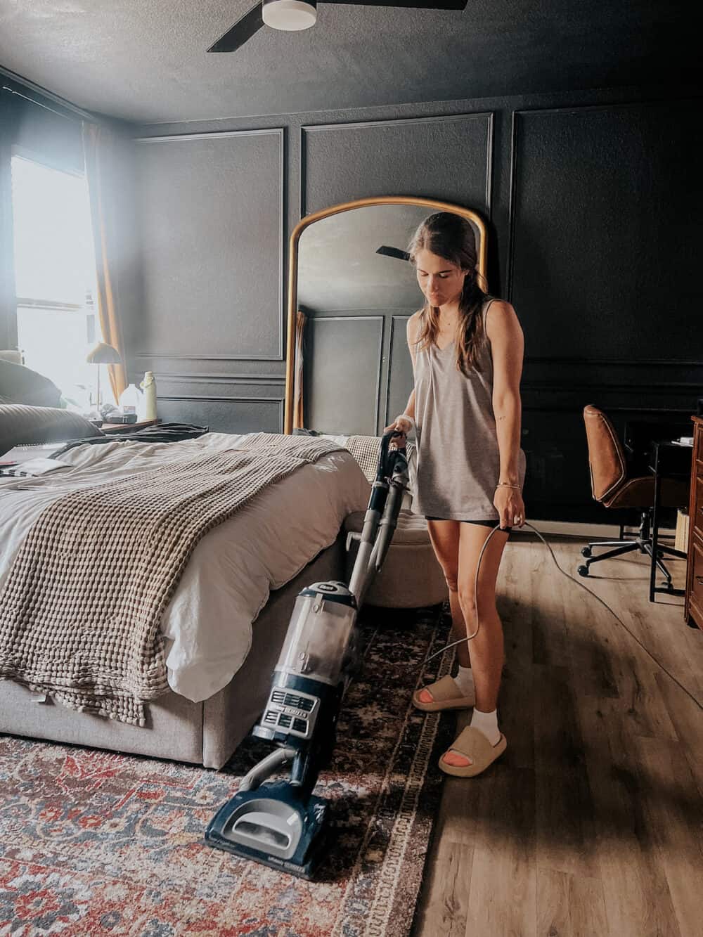 woman vacuuming an area rug in a bedroom 