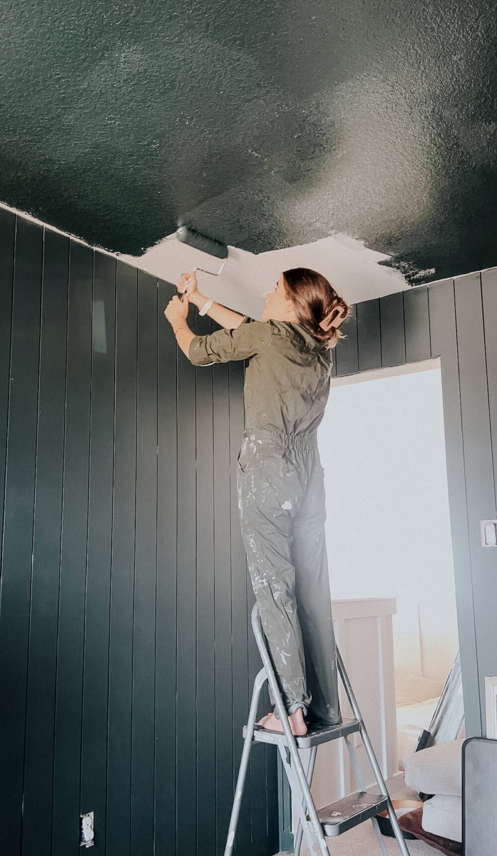 Woman painting a ceiling green