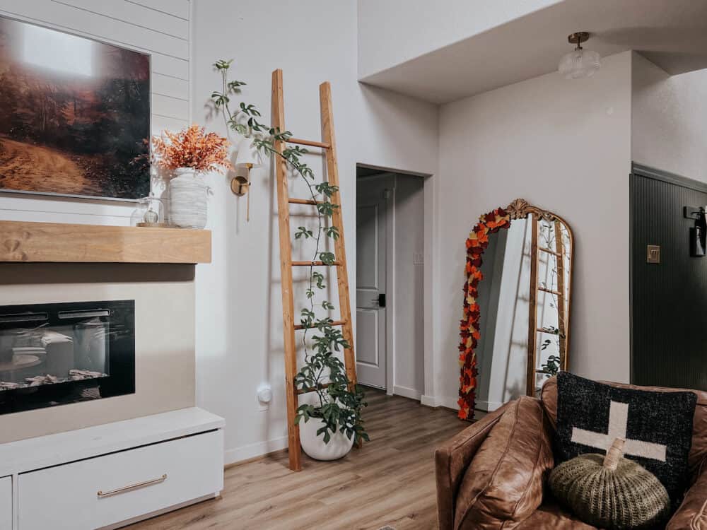 a living room decorated for fall with a mirror that has paper leaves on it