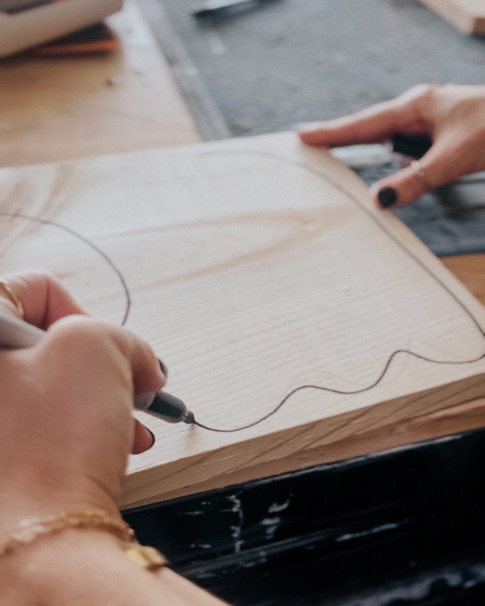 woman's hand drawing out a ghost shape on a piece of scrap wood