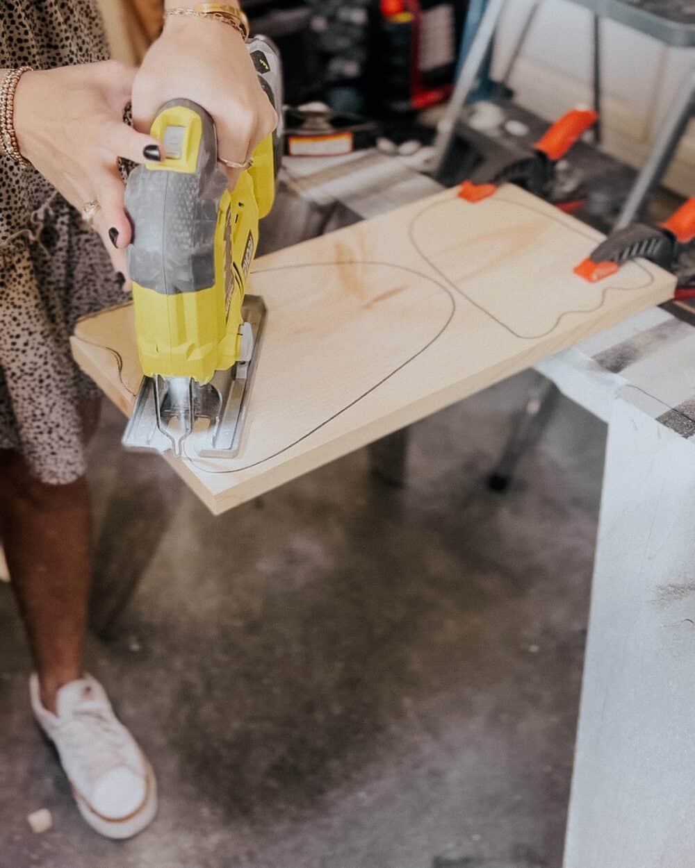 woman using a jigsaw to cut out a ghost from scrap wood